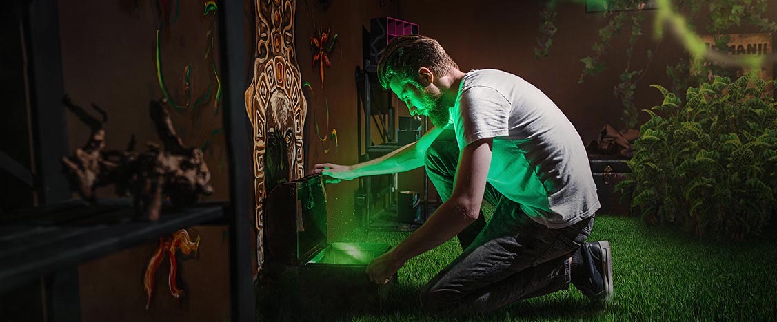 Player solving a puzzle in a green-lit jungle-themed escape room at 4 Dreams Escape Game in Denver