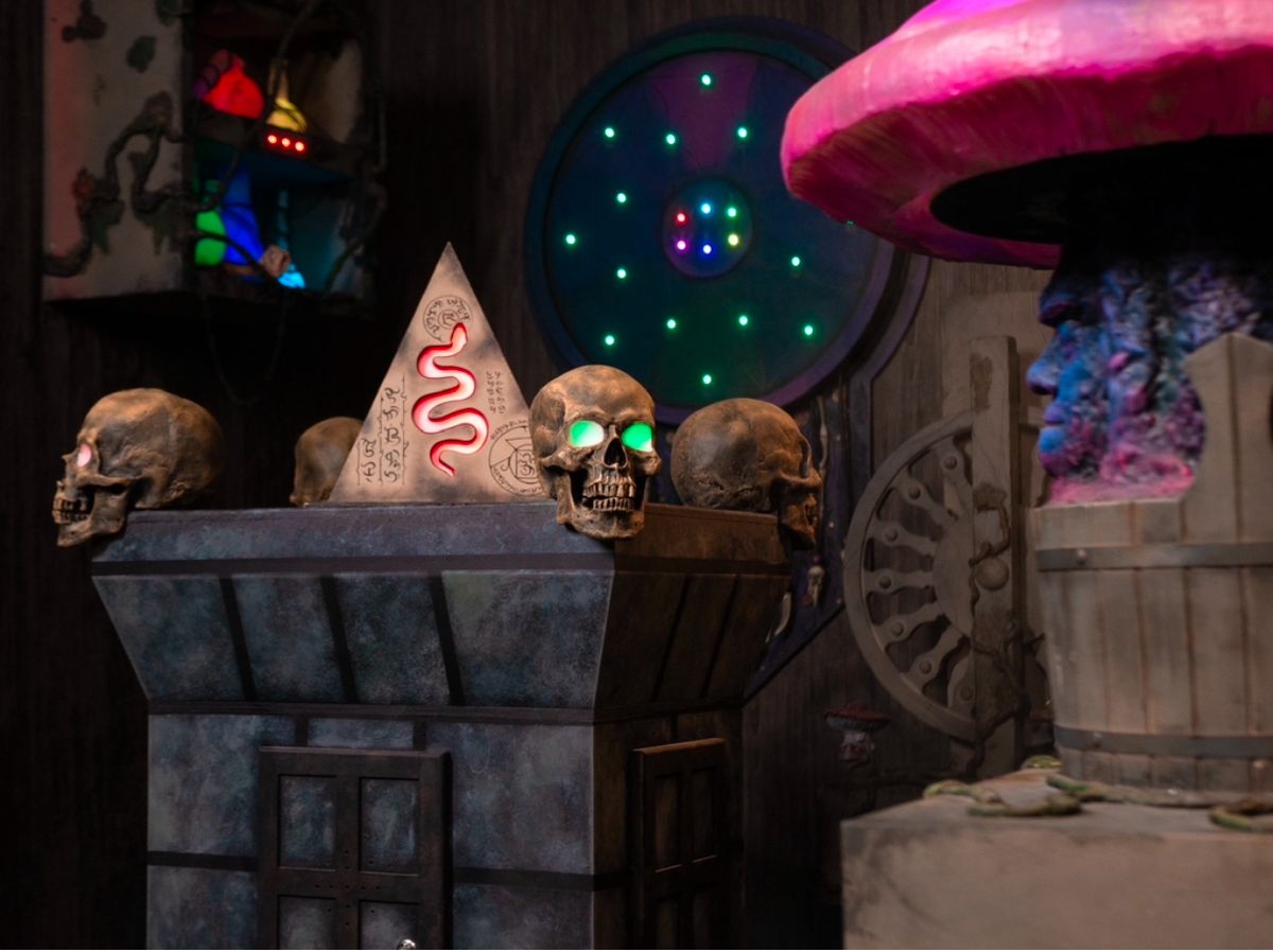 Skulls with glowing LED eyes, pyramid with snake symbol, and steampunk props inside The Dreams escape room
